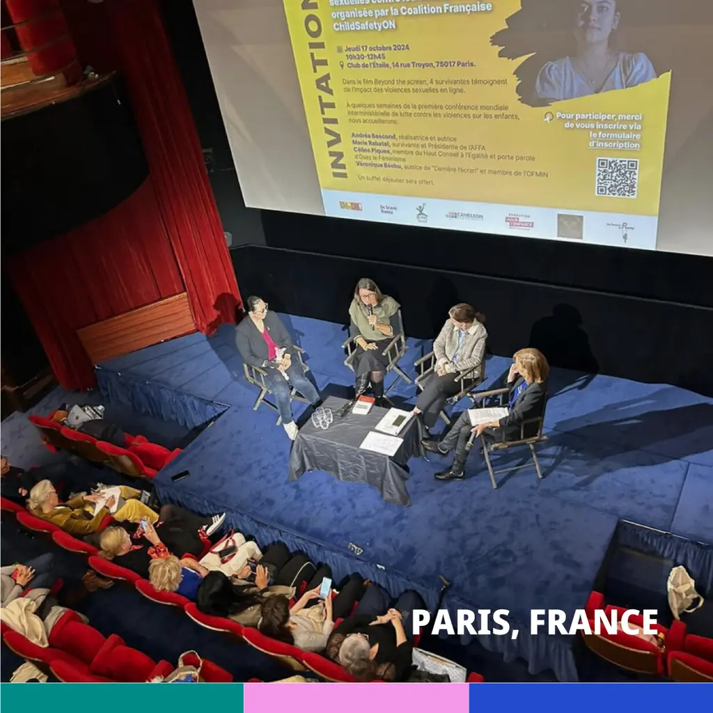 Group of people seated on a stage in an auditorium, with a projection screen displaying information about an event in Paris, France.