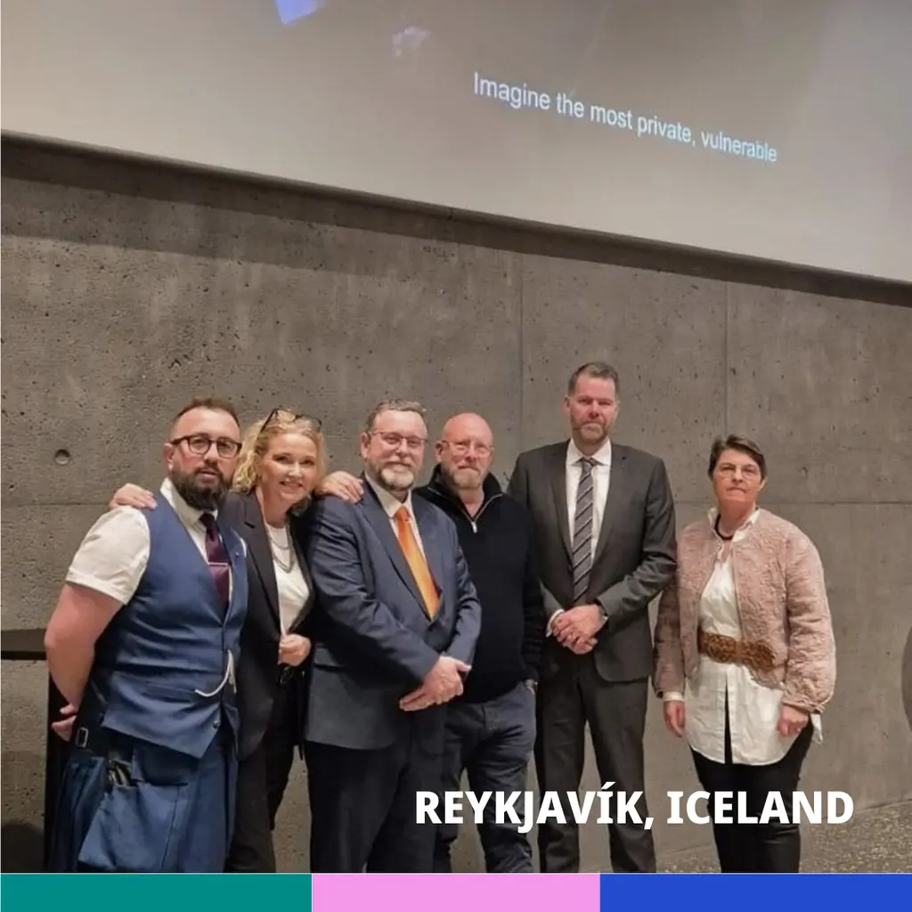 Group of 6 people, 4 men and 2 women, in formal business attire standing in front of a wall with the text "Imagine the most private, valuable" projected on it. Location is Reykjavík, Iceland.