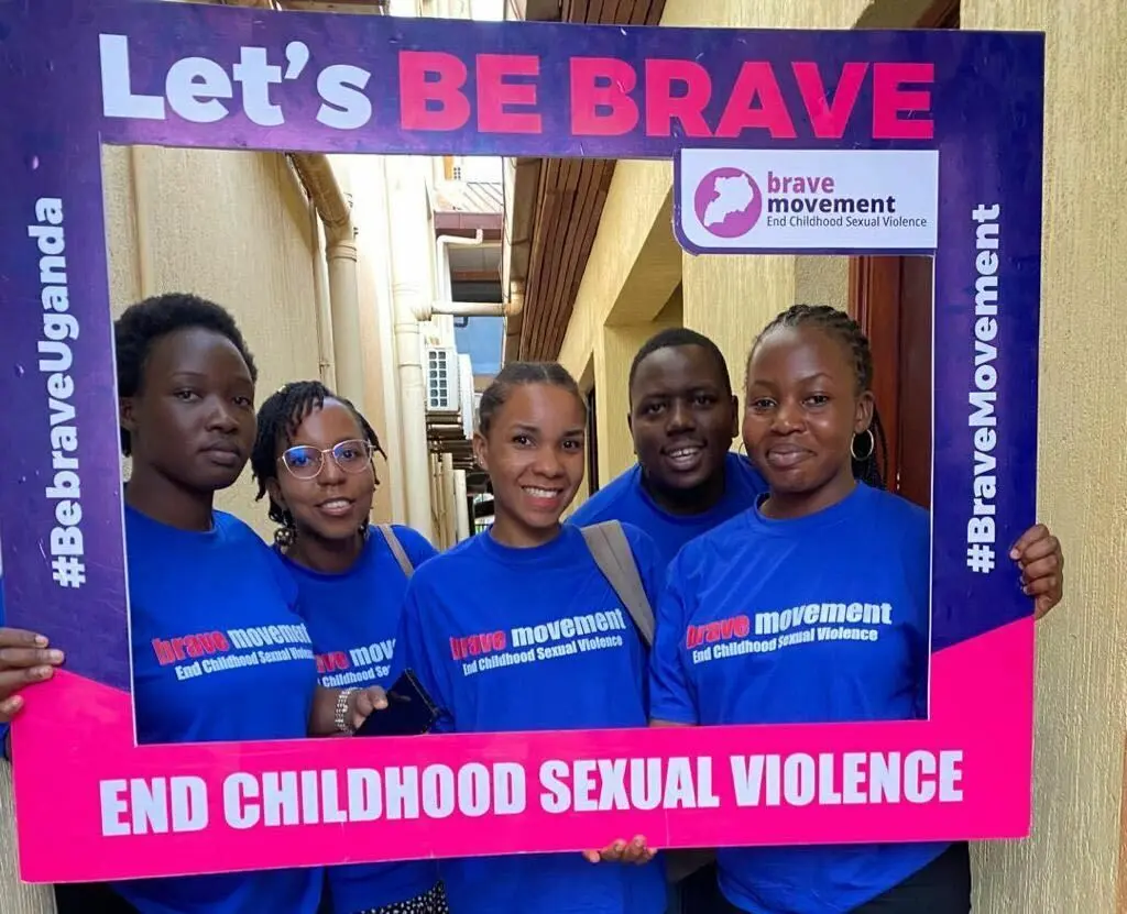 Image showing a group of 5 individuals, likely members of an organization called "Brave Movement", holding a sign that says "Let's BE BRAVE" and "END CHILDHOOD SEXUAL VIOLENCE". They are wearing matching blue t-shirts with the Brave Movement logo.