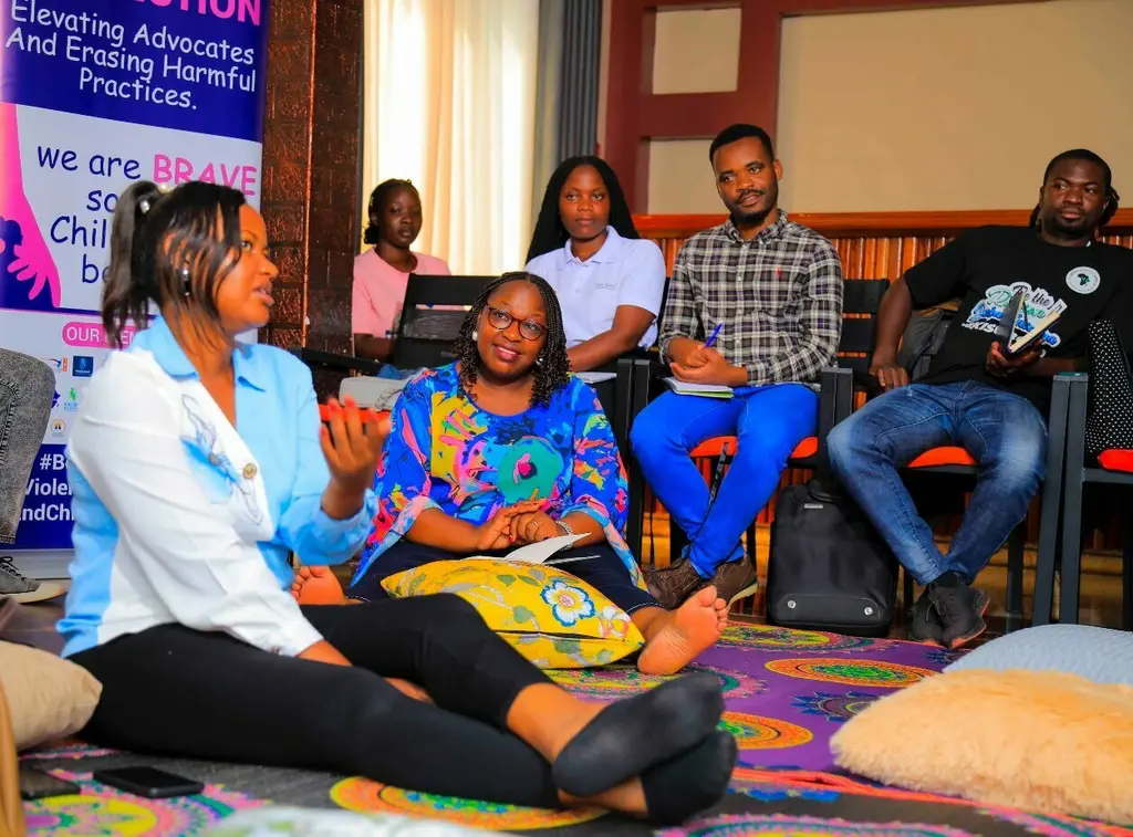 Diverse group seated in room, engaging in discussion or meeting.