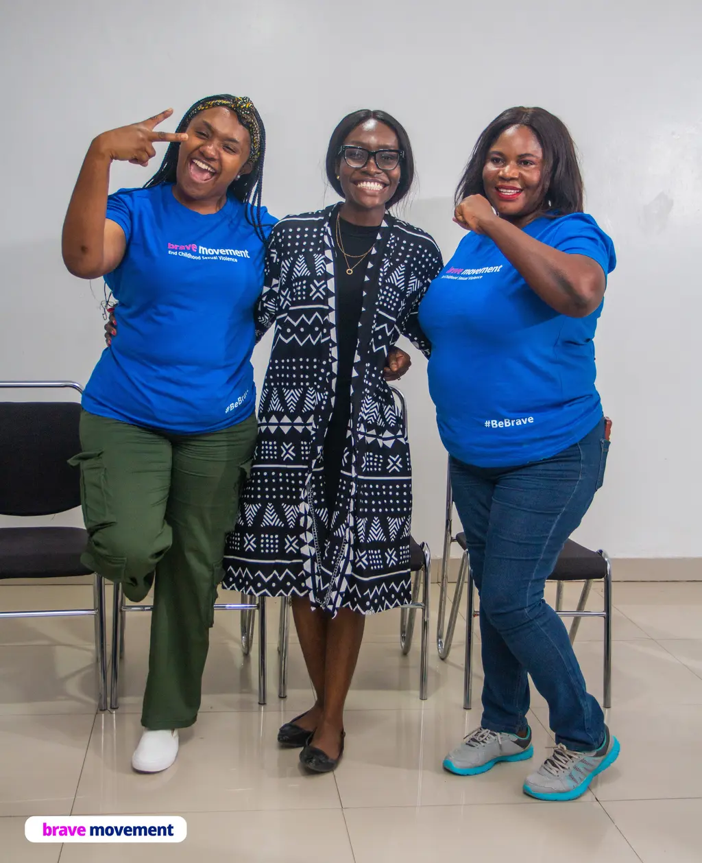 Three women wearing blue t-shirts with the "Brave Movement" logo, smiling and posing together.