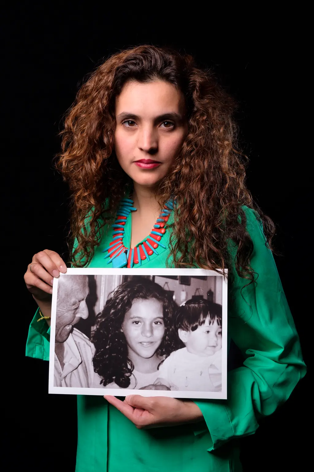 Person in green top holding black and white photo.