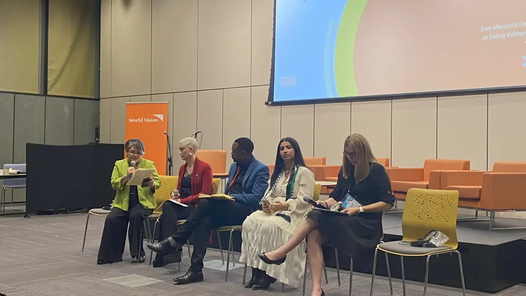 Group of 5 people seated at a conference table, with a projection screen visible in the background.