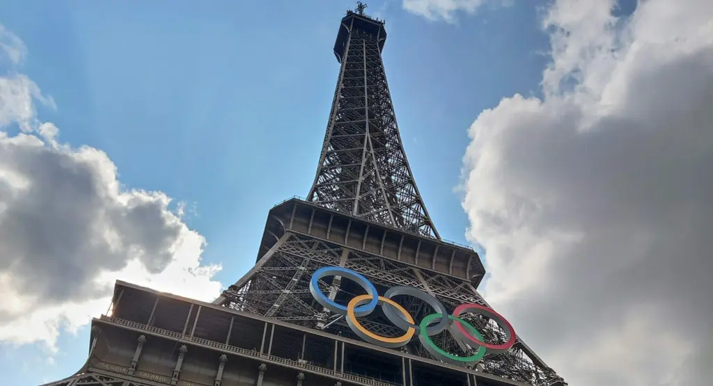 Eiffel Tower with Olympics rings, blue sky and white clouds.