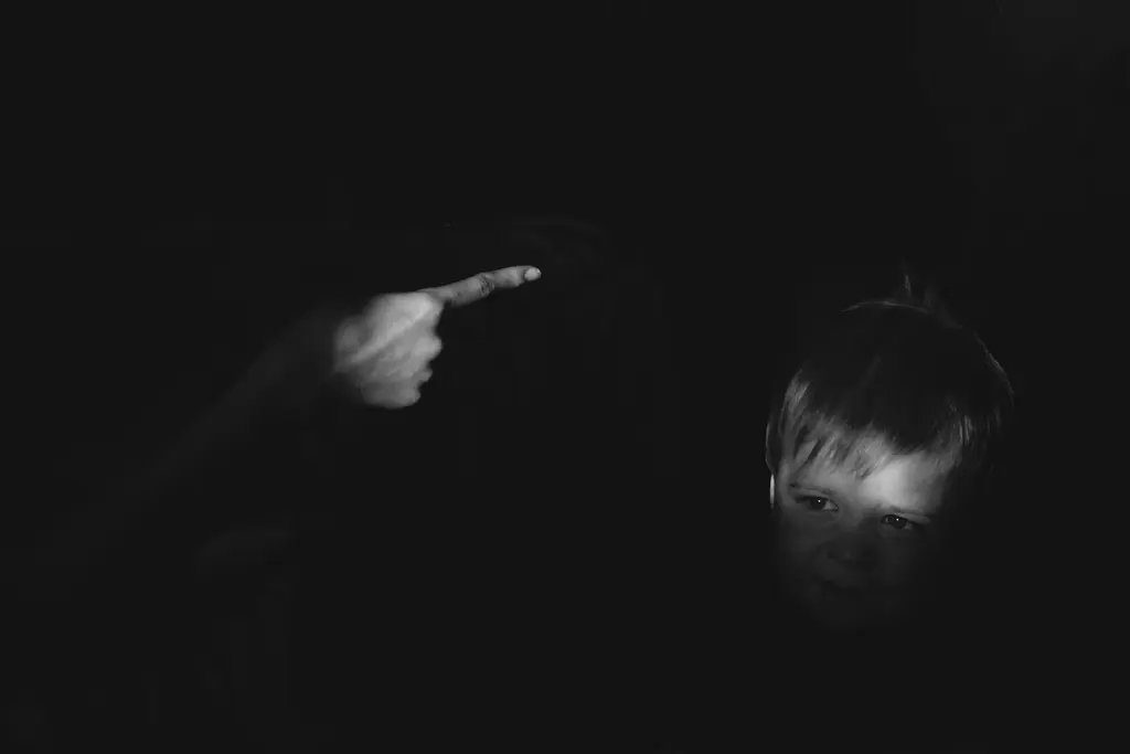 Monochrome image of a person pointing a handgun in the dark.