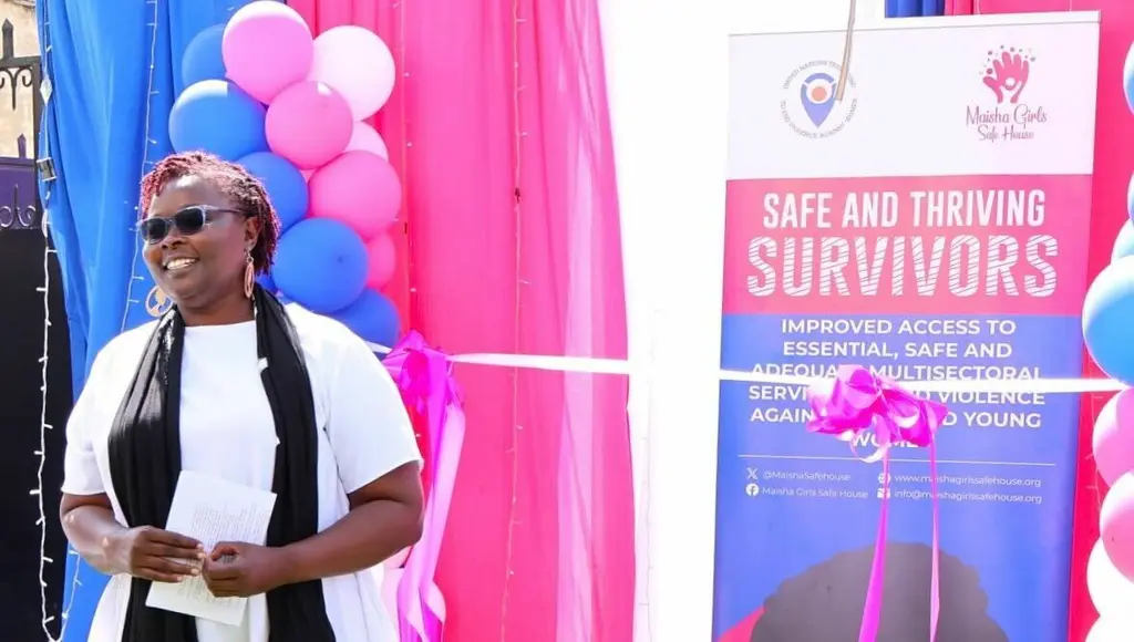 Colorful event banner with text "Safe and Thriving Survivors" and balloons. A person in a white shirt and sunglasses standing in front of the event banner.