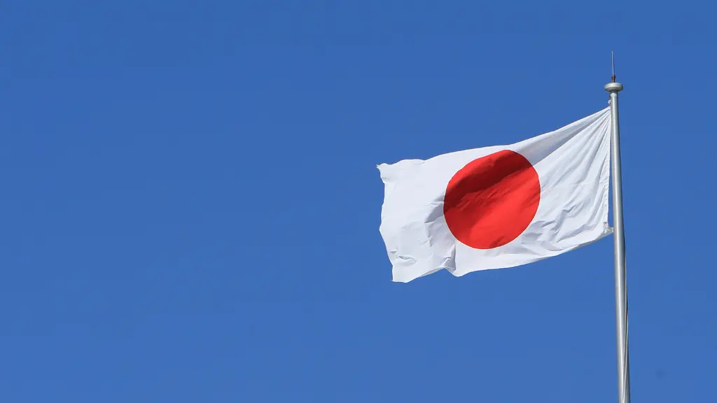 日本の国旗が青空に翻っている。赤い丸が白い布地に描かれ、引き上げられて空に立っている。