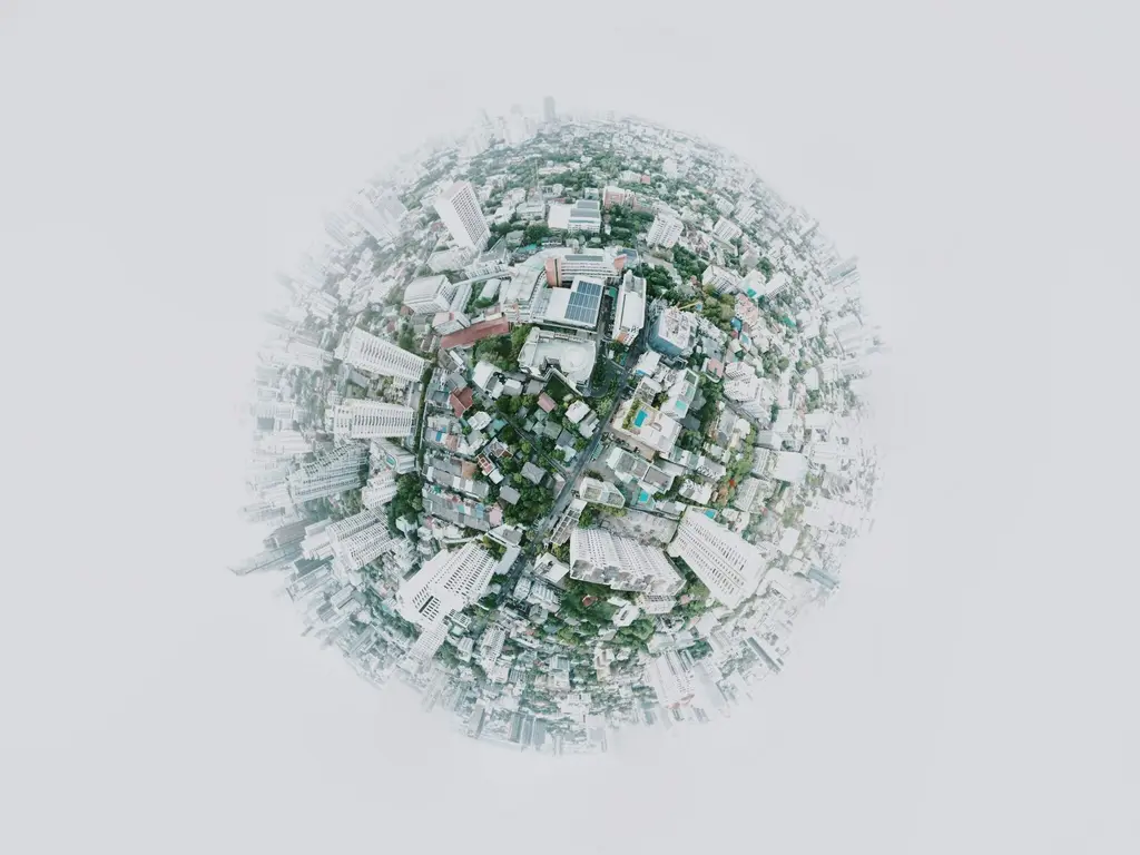 Aerial view of a densely populated urban area, with buildings, roads, and green spaces forming a spherical composition.