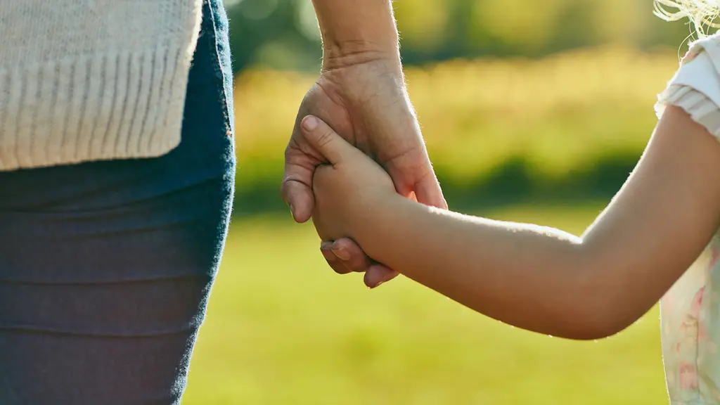 Two hands clasped together against a blurred green background.