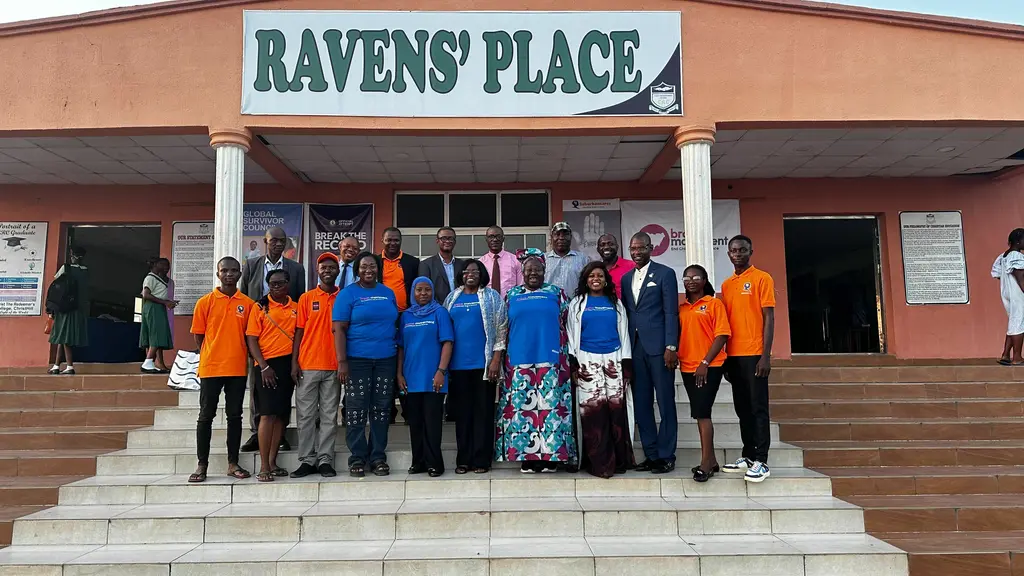 Large group of people posing together outside Ravens' Place building.