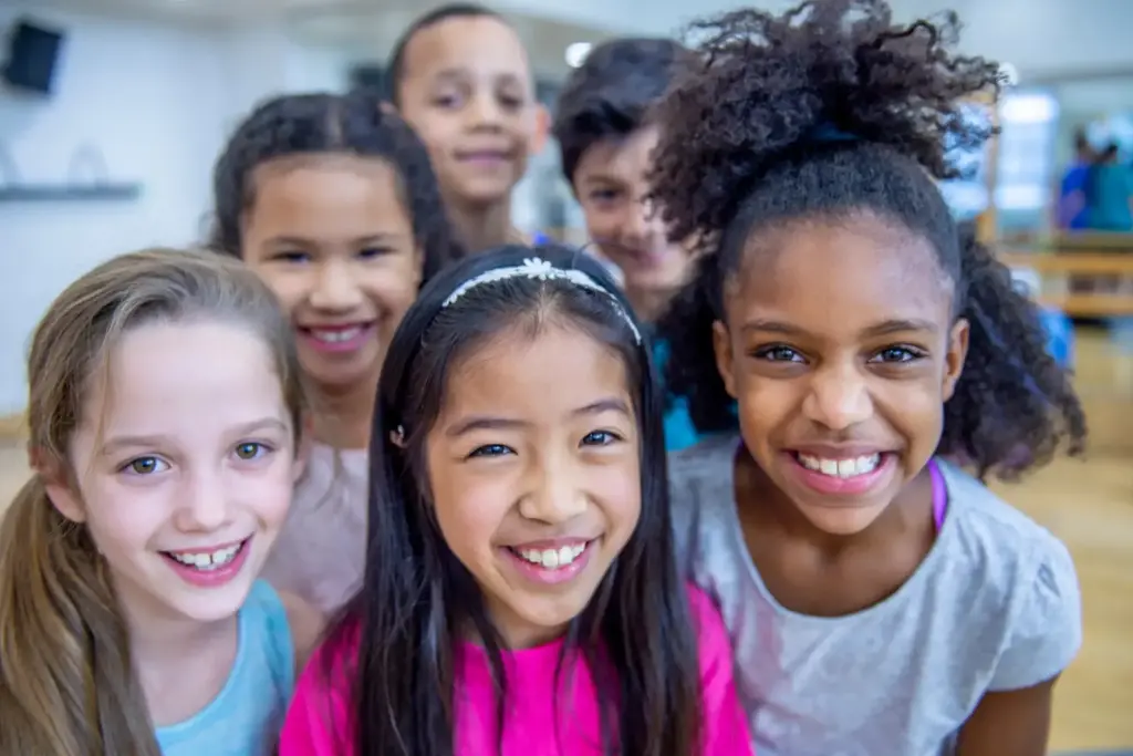 A group of smiling, happy children of diverse ethnic backgrounds.