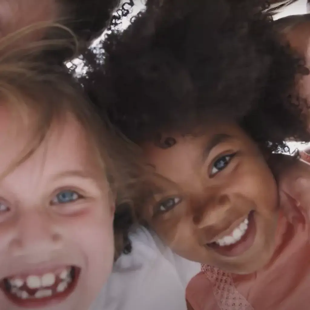 Three cheerful children with diverse appearances, smiling at the camera.