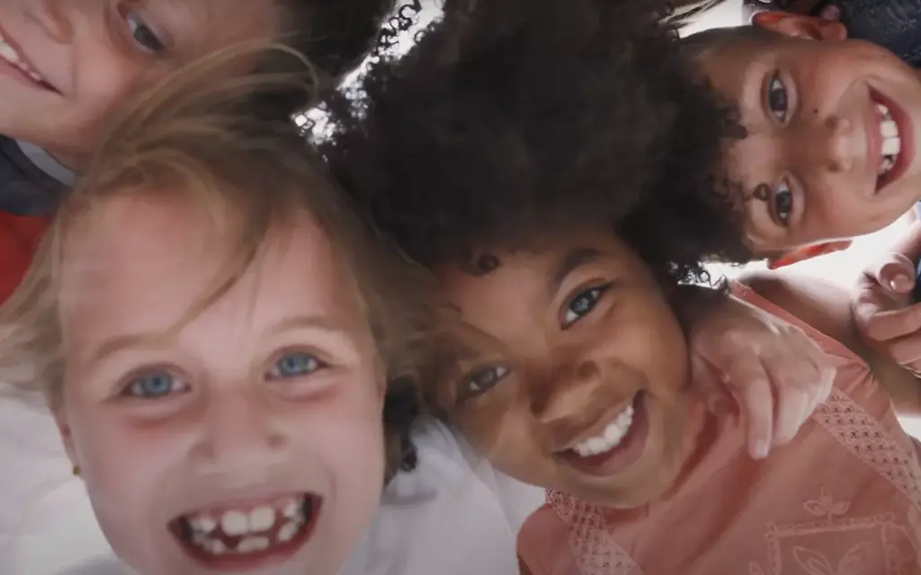 Three cheerful children with diverse appearances, smiling at the camera.