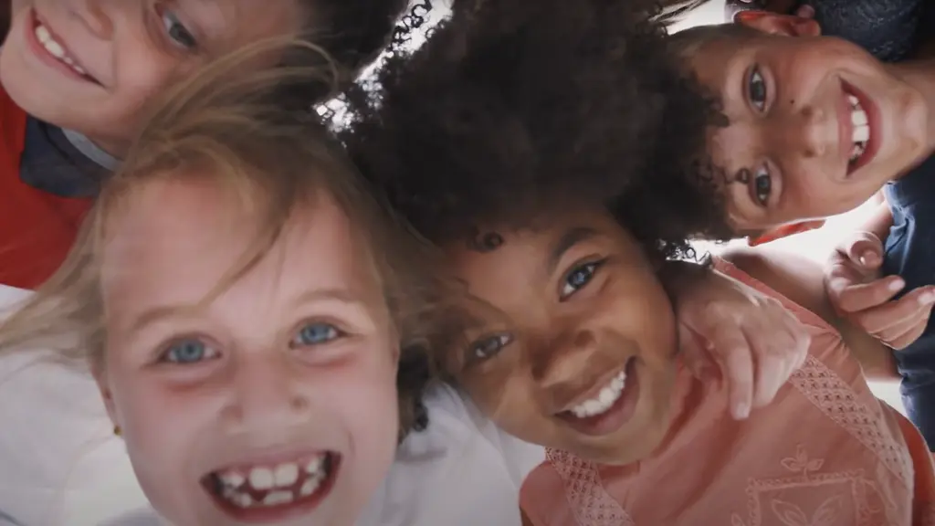 Smiling faces of 3 young girls with different skin tones and hair textures, looking directly at the camera.