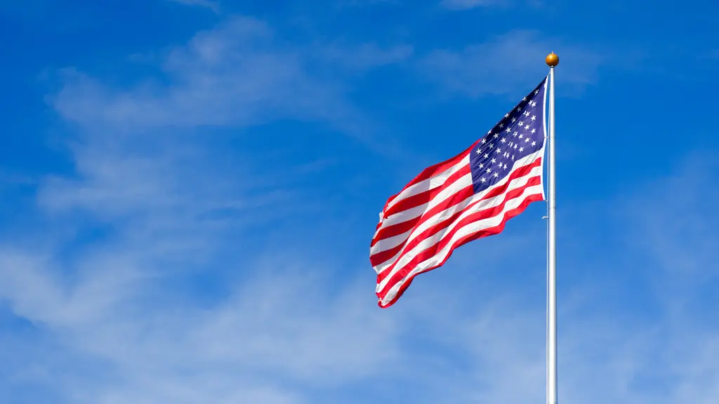 アメリカ国旗が青空に翻っています。旗は赤と白の縞模様で、星のパターンが付いています。